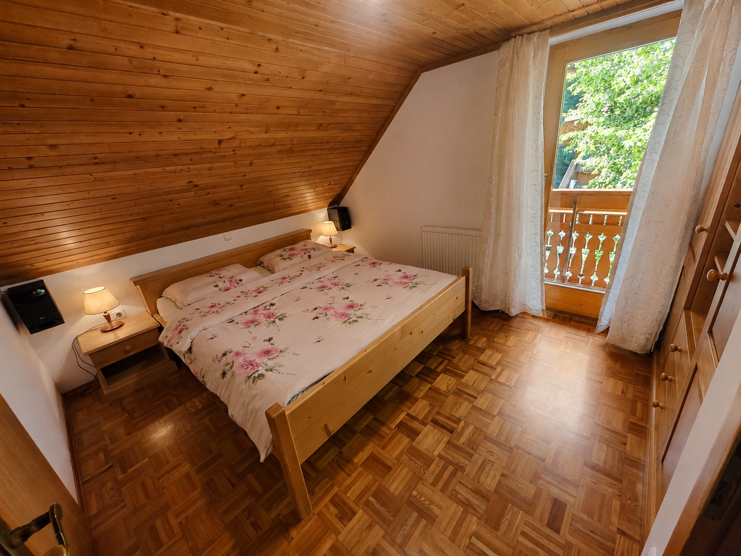 Spalnica 1 v leseni počitniški hiši — zakonska postelja in izhod na balkon